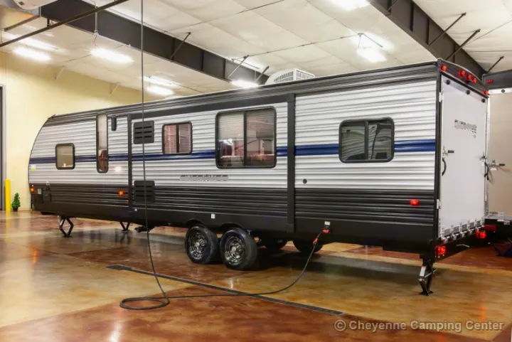 This large grey & black travel trailer, great for rv rental, is seen indoors. It features multiple windows & dual axles for camping.. Forest River Cherokee Grey Wolf 294rr 2020