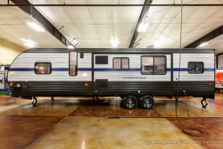 Side view of a grey and white travel trailer, an ideal RV rental for camping trips and outdoor adventures.. Forest River Cherokee Grey Wolf 294rr 2020