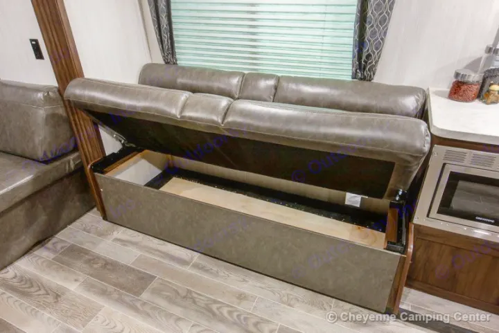 This RV rental features a gray leatherette couch with built-in, lift-up storage, showcasing efficient RV interior space.. Forest River Cherokee Grey Wolf 294rr 2020