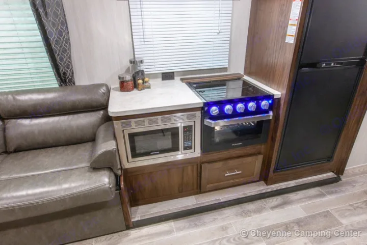 RV rental interior: kitchen with microwave, stove, fridge, next to a comfy couch.. Forest River Cherokee Grey Wolf 294rr 2020