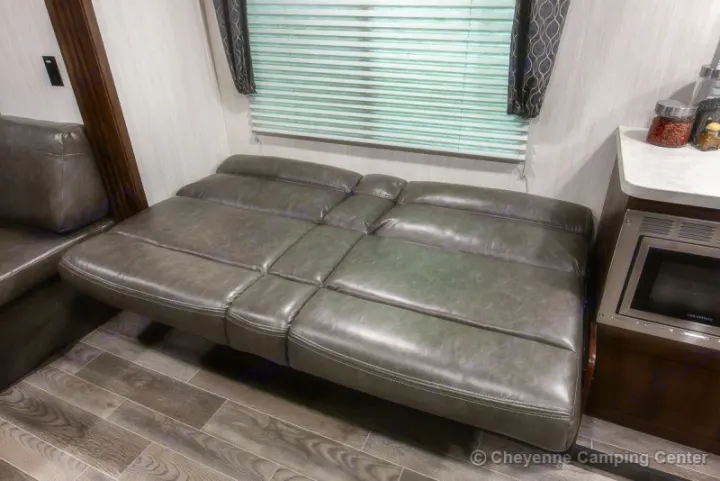 RV rental: A cozy interior with a gray sofa bed extended for sleeping. Features a counter and built-in microwave.. Forest River Cherokee Grey Wolf 294rr 2020