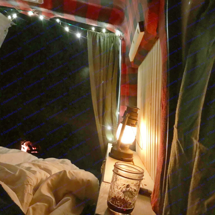 Enjoying a cozy night in an RV rental! Interior features string lights, a warm lantern, plaid walls, and a drink, offering true comfort.. Ford Custom Transit 2011