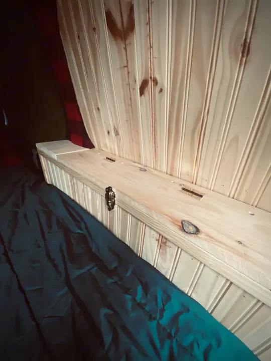 Experience this RV rental's cozy interior: light wood beadboard, hinged storage, & dark blanket on bed.. Ford Custom Transit 2011