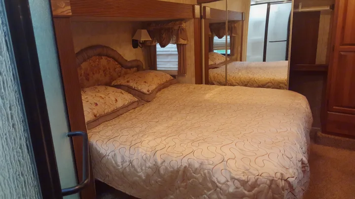 Spacious RV rental bedroom featuring a comfy bed, mirrored closet, and adjacent shower. Ideal for your travels!. Keystone Montana 2011
