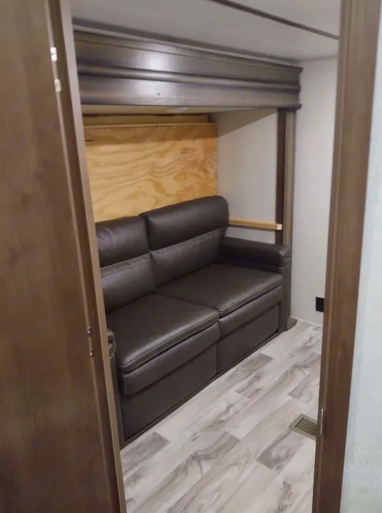 Inside an RV rental: cozy pull-out sofa & upper bunk, creating a functional compact living area.. Keystone Cougar 2019