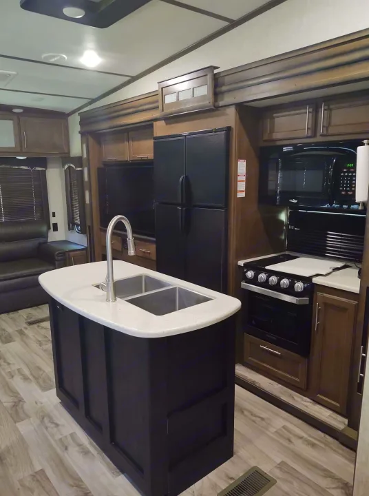 Modern RV rental interior featuring a full kitchen with island sink, appliances, and cozy living space.. Keystone Cougar 2019