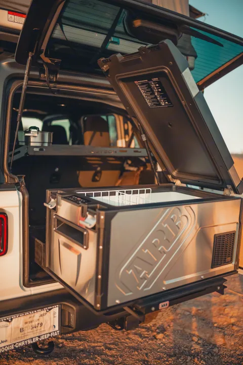 An RV rental Jeep's trunk open, revealing a slide-out ARB fridge/freezer, ideal for off-road camping trips.. Jeep Wrangler Unlimited 2020