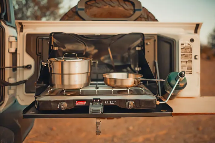 RV rental adventure: A Coleman Triton stove, pot & pan on a pull-out kitchen from an off-road vehicle, ready for camping.. Jeep Wrangler Unlimited 2020