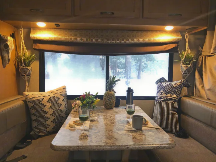 Cozy RV rental dining nook with breakfast & warm lights. Snowy winter outside, perfect for a cozy escape.. Other Four Winds 2018