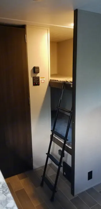 Experience comfort in this RV rental featuring a bunk bed setup with a ladder, wall controls, and stylish wood-look flooring.. Keystone Springdale 2019