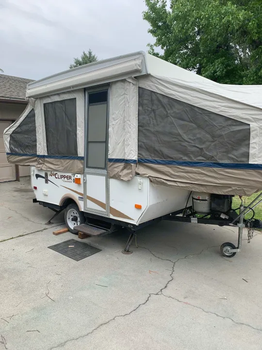 A white pop-up RV, a Clipper by Coachmen, fully set up on concrete. Perfect for an RV rental camping experience.. Coachmen Sport 2007