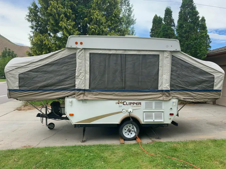 Pop-up RV rental: A Clipper by Coachmen, fully set up in a driveway with extended canvas, mesh windows, and stabilization jacks.. Coachmen Sport 2007
