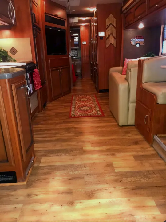 Step inside this inviting RV rental: a long aisle with wood flooring, full kitchen on left, and comfy living area on right. Ideal for road trips!. Fleetwood Class A 2015