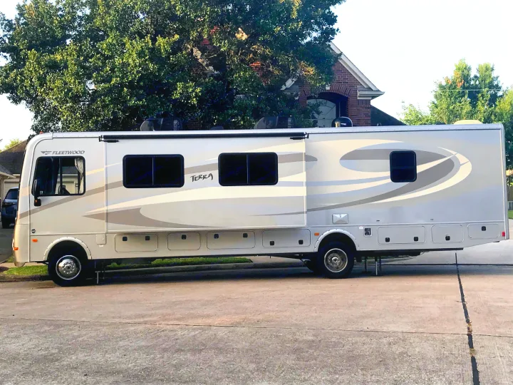Fleetwood Terra Class A motorhome, a great rv rental option. Light grey with graphic swirls, parked on pavement.. Fleetwood Class A 2015
