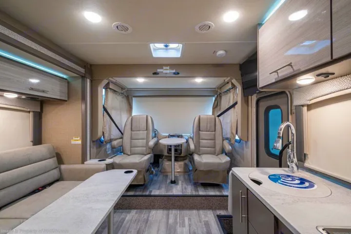 Spacious RV rental interior showcasing cockpit chairs, a sofa, and kitchen counter with sink.. Thor Motor Coach Vegas 24.1 2020