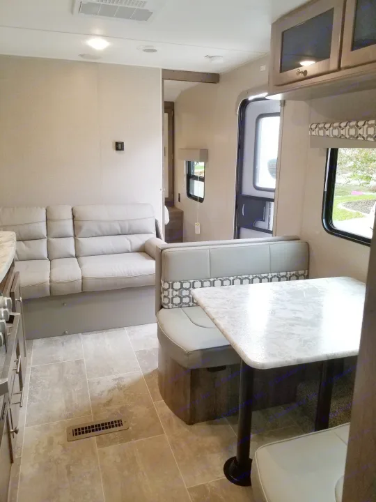 Spacious RV rental interior featuring a modern dinette, comfy sofa, and compact kitchen. Ideal for road trips.. Dutchmen Aspen Trail 2019
