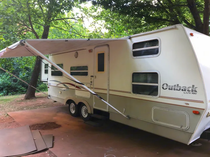 Outback travel trailer for rv rental, parked under trees with awning extended. Ready for your next adventure!. Keystone Outback 2003