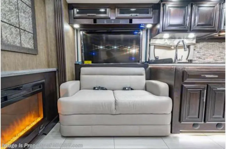 Cozy RV rental interior with a versatile sofa, TV, fireplace, and kitchen area for comfortable travel.. Forest River Berkshire 2020