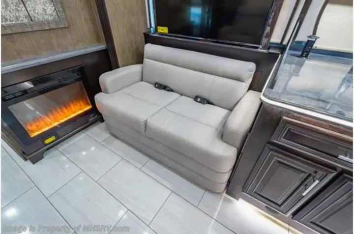 This RV rental offers a cozy living area with a light grey sofa, electric fireplace, and TV.. Forest River Berkshire 2020