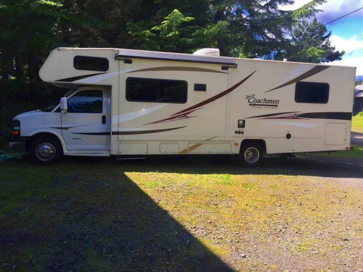 This large, white Coachmen Freelander Class C RV is parked on gravel and grass, ready for an RV rental adventure.. Coachmen Freelander 2014