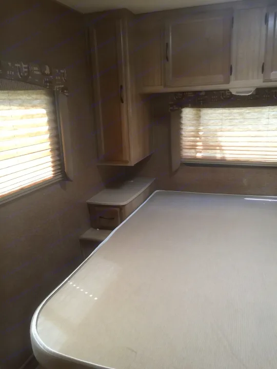 RV rental bedroom with light-filled windows, a mattress, and storage cabinets.. Coachmen Freelander 2014