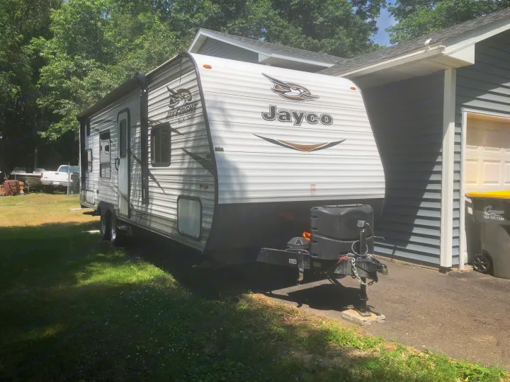 Jayco travel trailer RV rental, parked on green grass beside a house on a sunny day.. Jayco Jay Flight 2018