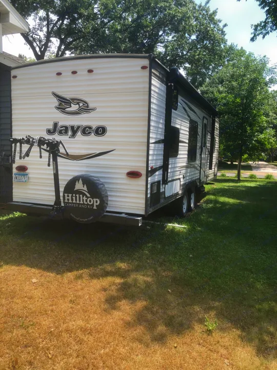 Jayco travel trailer with bike rack & Hilltop spare tire, parked in a sunny yard. Ideal for rv rental!. Jayco Jay Flight 2018