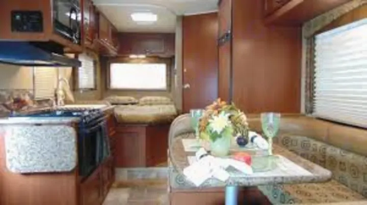 Inside this RV rental, find a compact kitchen, comfortable dinette with table setting, and a cozy bed in the rear.. Thor Freedom Elite 2020