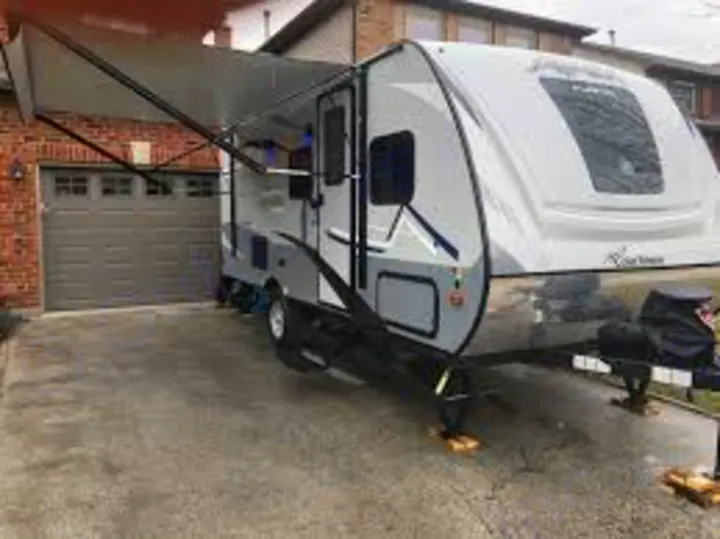 This sleek travel trailer, perfect for an RV rental, is parked in a home driveway with its awning extended, ready for adventure.. Apex Nano 193 BHS 2020