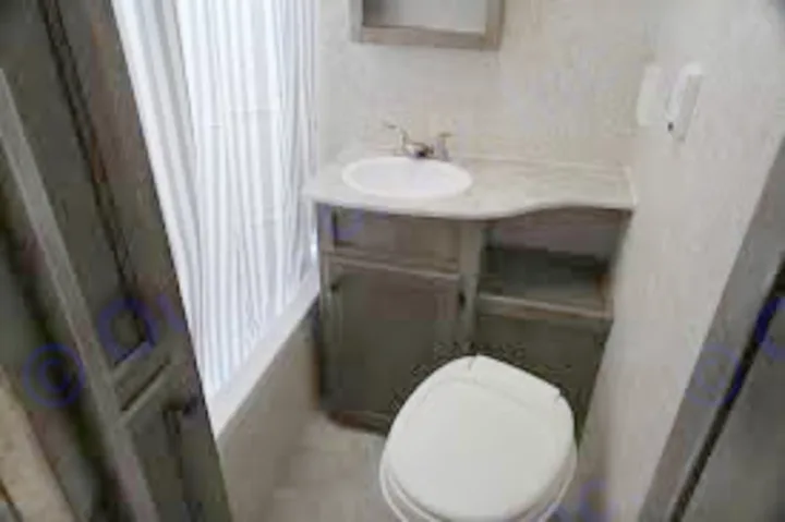Compact RV rental bathroom: Features a white toilet, vanity sink, and shower with a striped curtain, ideal for travel.. Apex Nano 193 BHS 2020