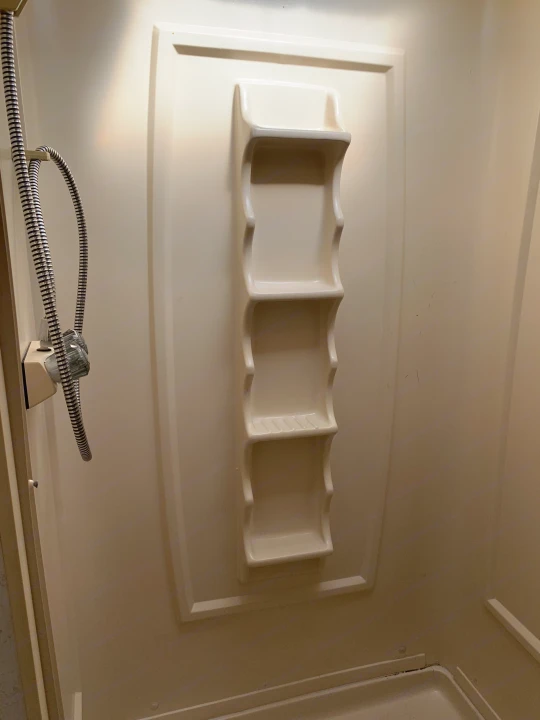 This RV rental shower features a handheld shower head and built-in shelving, offering functional space in a compact bathroom.. Majestic Leisure Craft E350 2001