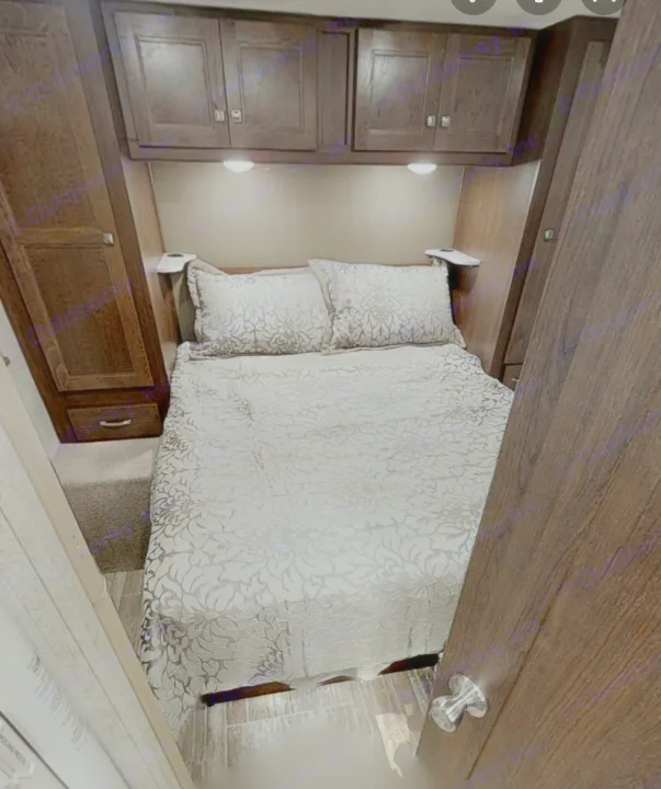 Cozy RV rental bedroom with patterned bed, overhead cabinets, and built-in storage.. Forest River Sunseeker 2020