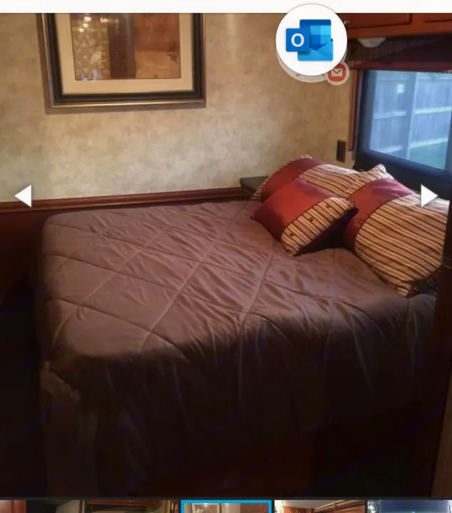 RV rental bedroom: a bed with a brown quilted comforter, striped pillows, and a window offering outdoor views.. Winnebago Vista 2013
