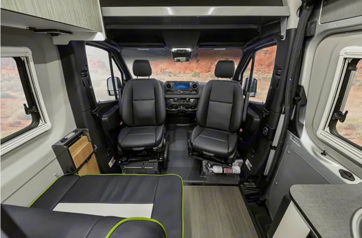 Step inside this RV rental! View of the front cabin with black leather swiveling seats, dashboard, and scenic desert views through large windows.. Winnebago Revel 2020