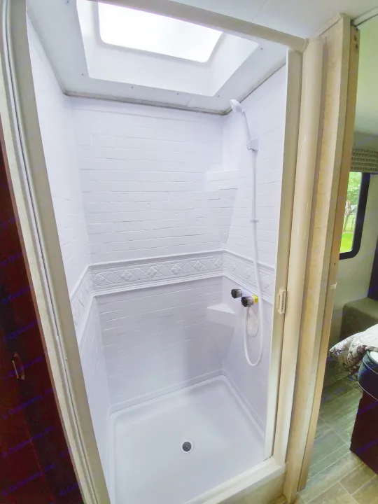 Inside an RV rental: a bright, white shower stall with a skylight, perfect for refreshing on your journey.. Forest River Sunseeker 2020