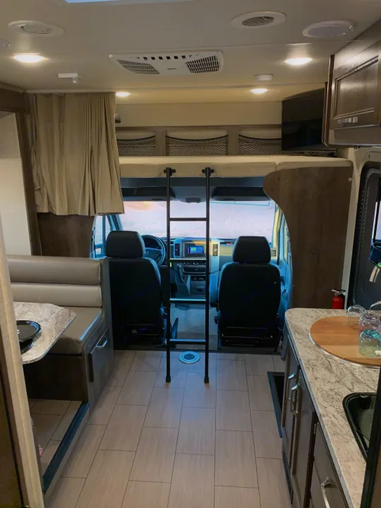 Cab with swivel captain chairs. over the cab bed with ladder, privacy curtain and TV. Jayco Melbourne 2019