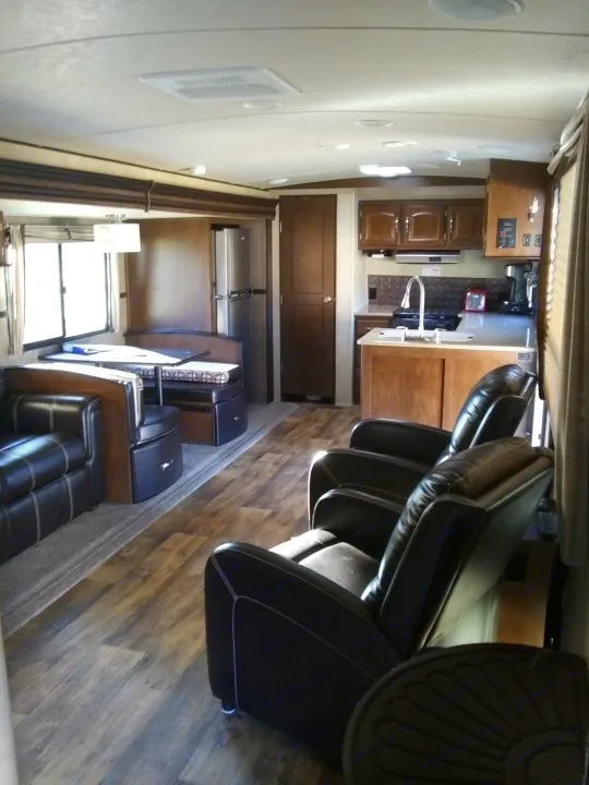 RV rental interior: living space with black recliners, kitchen featuring wood cabinets, and dining area with modern wood-look flooring.. Forest River Salem Hemisphere 2017