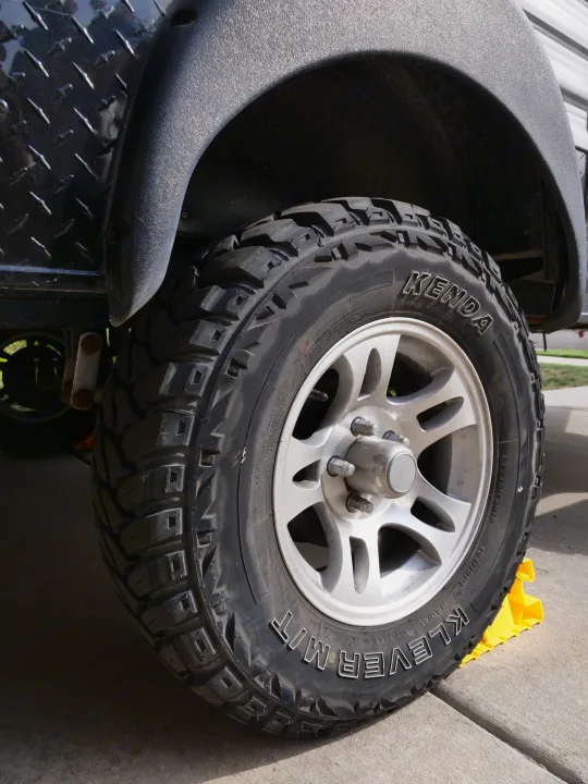 Close-up of a Kenda Klever M/T tire on an RV rental trailer, safely chocked. Shows wheel, tread, and fender details.. Gulf Stream Innsbruck 2016