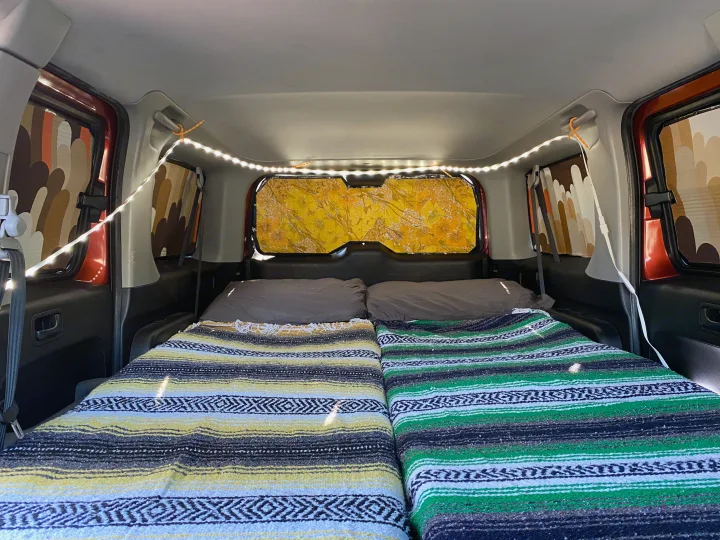 RV rental interior with two beds made up with vibrant blankets, soft pillows, LED lighting, and custom privacy window covers.. Honda Element 2005
