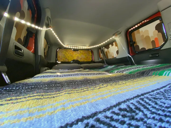 Cozy vehicle interior, ideal for an RV rental. Features bright LED lights, custom window shades, and a comfy striped bed.. Honda Element 2005