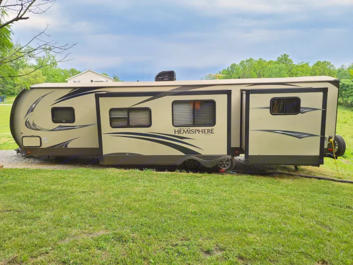 This spacious RV rental, a Salem Hemisphere Lite travel trailer, is parked and set up for camping in a grassy area.. Forest River Salem Hemisphere 2015