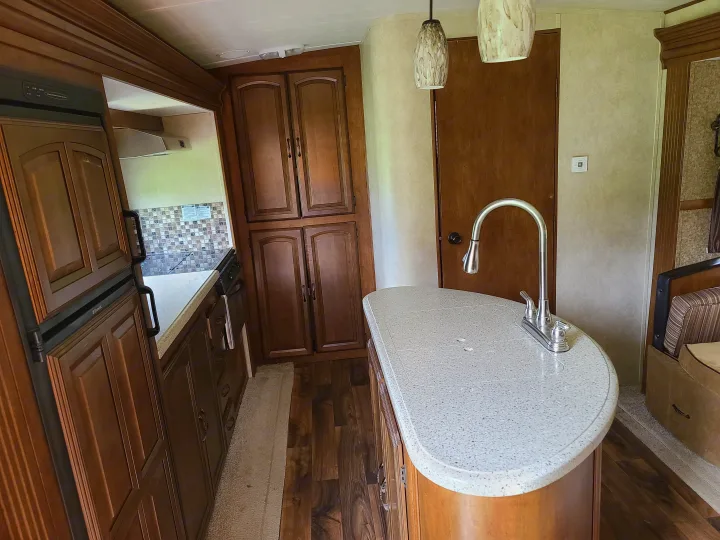 Inside a cozy RV rental, showcasing a modern kitchen island with sink, refrigerator, and seating. Ideal for travel.. Forest River Salem Hemisphere 2015