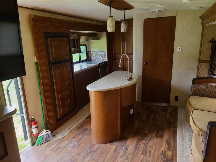 Clean and spacious RV rental kitchen interior, featuring an island, wooden cabinets, and a microwave. Ideal for travel.. Forest River Salem Hemisphere 2015