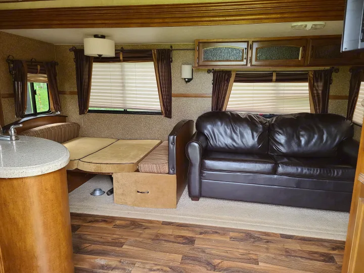 Cozy RV rental interior: spacious living area with leather sofa, dinette bed, sink, and overhead storage.. Forest River Salem Hemisphere 2015