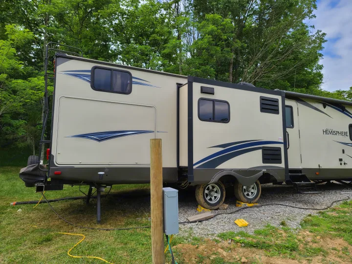 RV rental travel trailer parked at a leafy campsite with slide-outs extended, ready for a comfortable stay.. Forest River Salem Hemisphere 2015