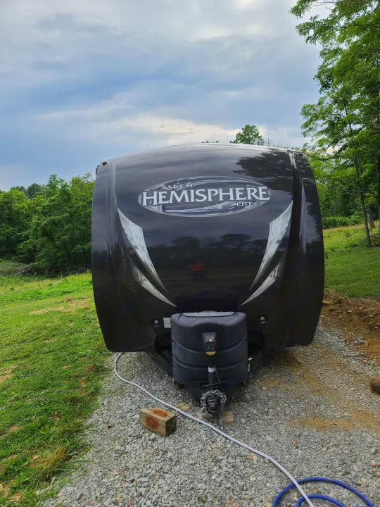 Black Salem Hemisphere Lite travel trailer with propane tanks and hitch, parked on gravel. Perfect for an rv rental getaway.. Forest River Salem Hemisphere 2015
