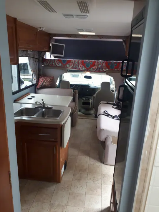 Step inside this RV rental, featuring a full kitchen, living area, overhead bunk bed, and driver's cockpit.. Other Other 2009