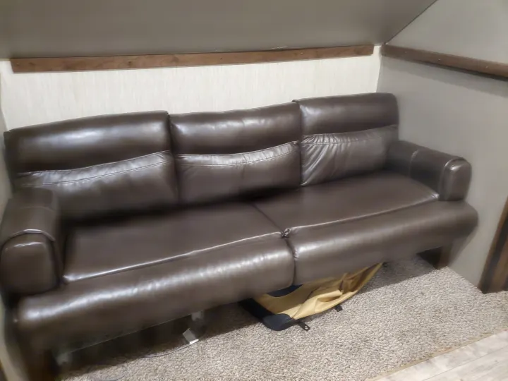 Brown leather RV rental sofa with two reclining seats on a textured carpet floor.. Other Other 2019