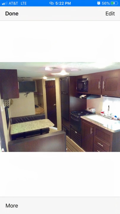 Interior view of an RV rental showing the kitchen, dining booth with a TV, and a glimpse of bunk beds in the back.. kz 26' SPORTSMAN 2018
