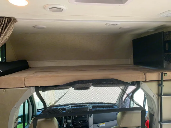 RV rental interior: view of the overhead bunk bed with cushions, TV, and a safety net above the front cab.. Forest River Sunseeker 2019